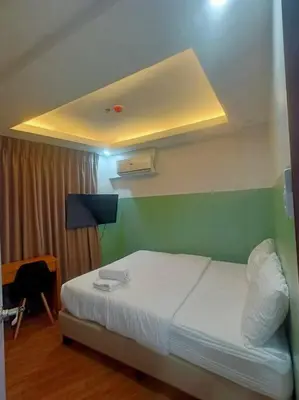 a bedroom with a white bed and a green wall at St. Marvin Studio Makati M301 in Manila