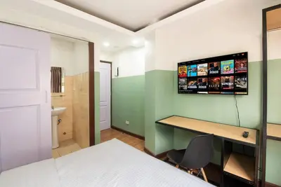 a bedroom with a bed and a desk and a television on the wall at St. Marvin Studio Makati M203 in Manila