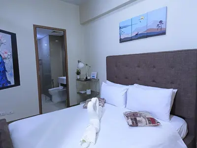 a bedroom with a bed with white sheets and a mirror at Palmtree Two Villas Across Terminal 3 or Manila Airport in Manila