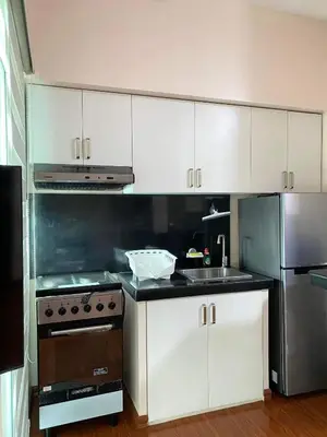a kitchen with white cabinets and a stainless steel refrigerator at Anuva Residence Condominium in Manila