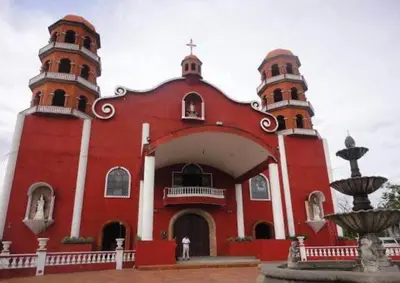 a red church with two towers and a fountain at Neat Unit in Holland Park Southwoods in Biñan