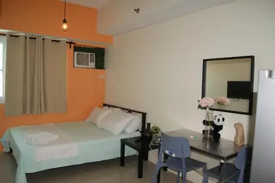 a bedroom with a bed and a desk with a mirror at The Beacon Makati by mvmtransient in Manila