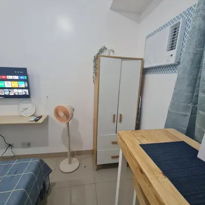 a room with a bed and a table and a cabinet at Homely Green 2 Residences T2 in Dasmariñas