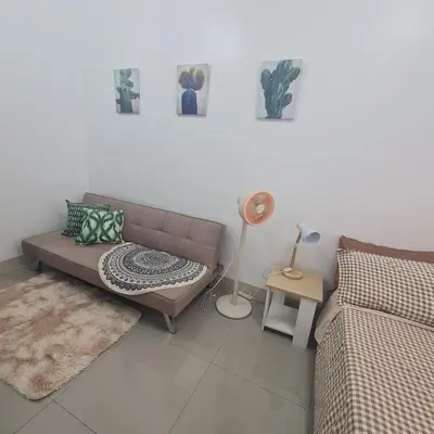 a living room with a brown couch and a lamp at HOMELY @ Green 2 Residences SMDC DLSUMC in Dasmariñas