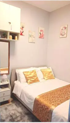 a bedroom with a bed with white sheets and gold pillows at FourSphere staycation in Manila