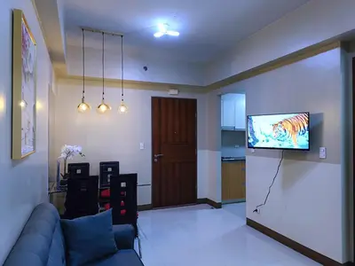 a living room with a couch and a flat screen tv at 1BR at TWO PALMTREE VILLAS Across Manila airport terminal 3 in Manila