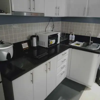 a kitchen with white cabinets and a microwave on a counter at Cozy condo with balcony in Taguig in Manila