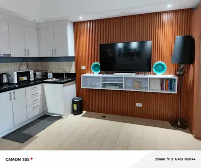 a kitchen with a flat screen tv on a wall at Cozy condo with balcony in Taguig in Manila