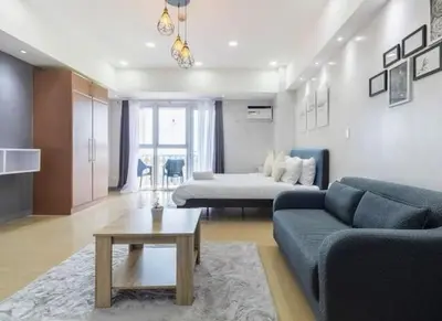 a living room with a couch and a bed at Cozy condo with balcony in Taguig in Manila
