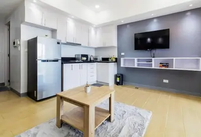 a large kitchen with a table and a refrigerator at Cozy condo with balcony in Taguig in Manila