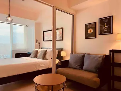 a hotel room with a bed and a couch at Relaxing 1-Bedroom Unit in Azure Urban Resort and Residences by One Guest Place in Manila