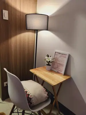 a desk with a chair and a table with a lamp at Fame Residences Staycation in Manila