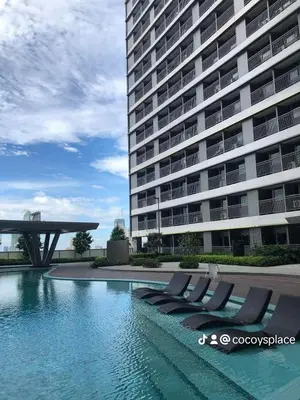 a swimming pool with lounge chairs in front of a building at Fame Residences Staycation in Manila