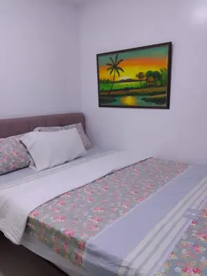 a bedroom with a bed with a painting on the wall at Birch Tower in Manila