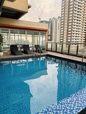 a large swimming pool with chairs on a building at Birch Tower in Manila