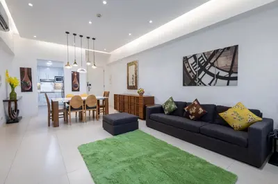 a living room with a black couch and a green rug at NEW 2BR of 86sqm with Parking & Netflix in BGC in Manila