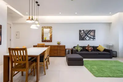 a dining room and living room with a table and a couch at NEW 2BR of 86sqm with Parking & Netflix in BGC in Manila