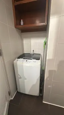 a small washing machine in a corner of a kitchen at KL Rooms at Greenbelt makati with cityview in Manila