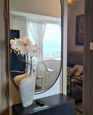a vase with flowers on a table in front of a mirror at Cozy Comfy Suite 2BR w Balcony - Amazing Manila Bay View and City Skyline near MOA in Manila