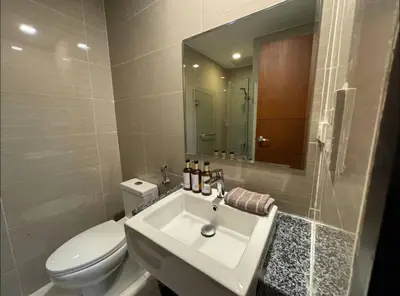 a bathroom with a sink and a toilet and a mirror at Modish 1BR One Uptown BGC direct to Uptown Mall in Manila