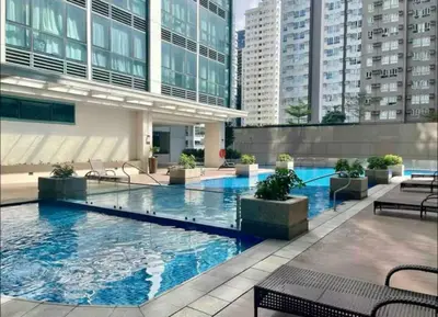 a large swimming pool in a building with tall buildings at Modish 1BR One Uptown BGC direct to Uptown Mall in Manila