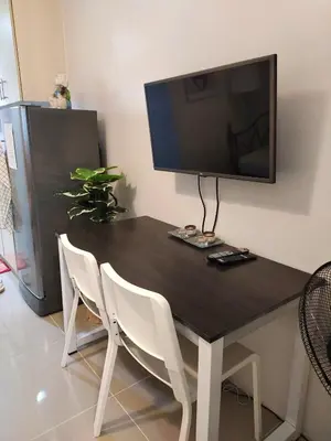 a black table with white chairs and a flat screen tv at Sea Residence Finest in Manila