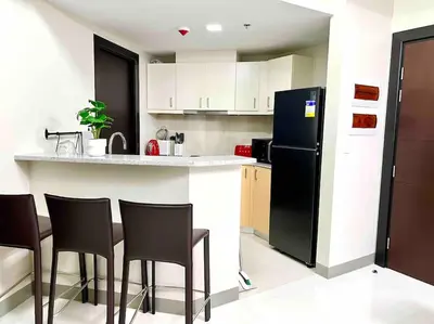 a kitchen with a black refrigerator and some chairs at Cozy 2 Bedrooms in BGC with Balcony Bathtub 600Mbps in Manila