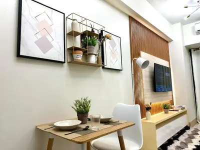 a dining room with a wooden table and white chairs at SMDC Shore 3 Residences - One Bedroom Unit in Manila