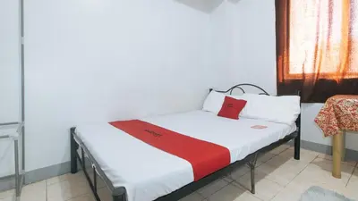 a small bed with a red and white blanket on it at MCP Transient near NAIA in Manila