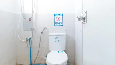 a bathroom with a toilet and a sign on the wall at MCP Transient near NAIA in Manila