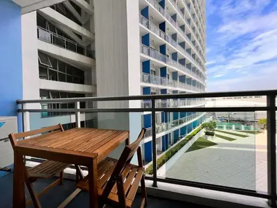 a balcony with a wooden table and chairs on a building at Manila Philippines, Azure Urban Resort Staycation by Leroche near Ninoy Aquino International Airport in Manila