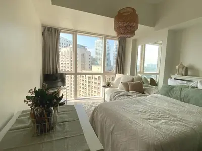 a bedroom with a bed and a large window at -CONDO- Petite Residential Stay in Manila