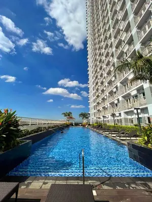 a swimming pool in front of a large building at Cozy Penthouse 2BR Suite w Balcony - Amazing Manila Bay View and City Skyline near MOA in Manila