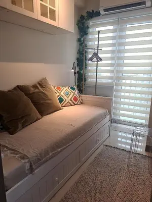 a bed sitting in a room with a window at Cozy Penthouse 2BR Suite w Balcony - Amazing Manila Bay View and City Skyline near MOA in Manila