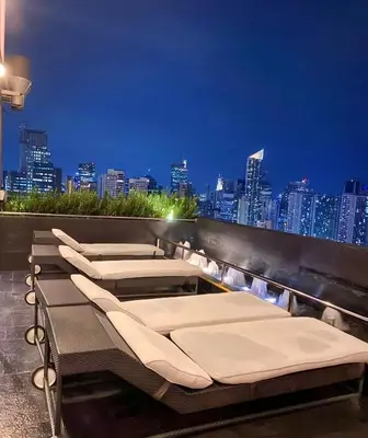 a row of beds on a rooftop with a city skyline at Homestead in Manila