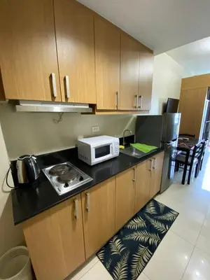 a kitchen with wooden cabinets and a microwave on a counter at Shell Residence Moa - Anne in Manila