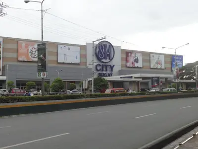 a building with a city sign on the side of a street at Cozy Studio Unit near Manila Airport With Swimming Pool, Full Kitchen 7A in Manila