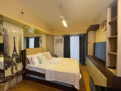 a bedroom with a large bed and a television at Modern Bayview Condo in 8 Adriatico in Manila