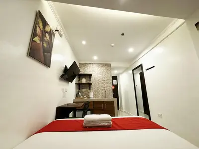 a bedroom with a bed with a red blanket at Nest Fort BGC in Manila