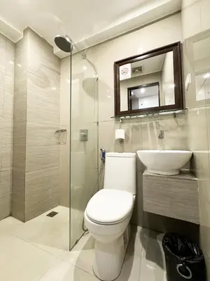 a bathroom with a toilet and a sink and a mirror at Nest Fort BGC in Manila