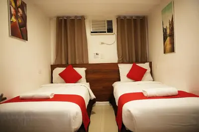 two beds in a hotel room with red pillows at Nest Fort BGC in Manila