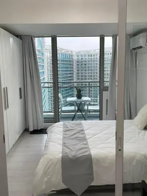 a bedroom with a bed and a balcony with a table at Azure Urban Resort Residences in Manila