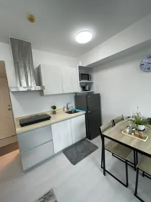 a kitchen with a table and a black refrigerator at Azure Urban Resort Residences in Manila