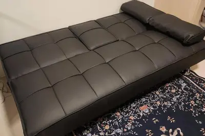 a black leather couch in a room with a rug at Chill Apartment in Makati in Manila