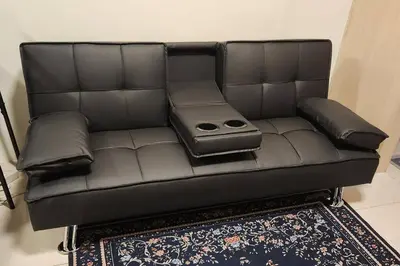 a black leather couch with pillows on a rug at Chill Apartment in Makati in Manila