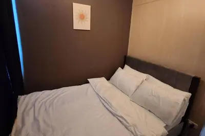 a bed with white sheets and a picture on the wall at Chill Apartment in Makati in Manila