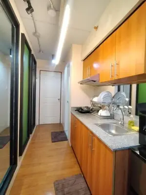 a kitchen with wooden cabinets and a sink and a hallway at Brand New Studio in Pasig with Free Pool Access in Manila