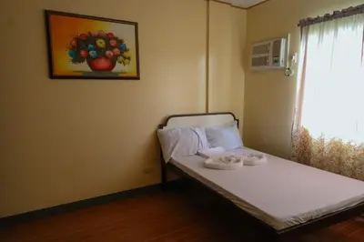 a small bedroom with a bed with a painting on the wall at Villa Elsie Resort and Hotel in General Trias