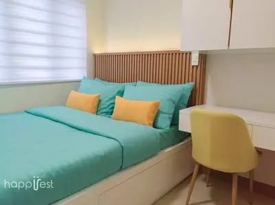 a bed with blue and orange pillows and a chair at Happirest at S Residences w/Balcony, Mall of Asia in Manila