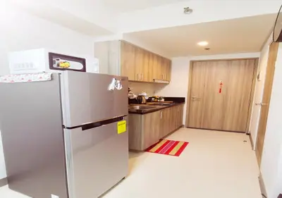 a kitchen with a stainless steel refrigerator and wooden cabinets at S Residences1 bedroom with balcony near MOA in Manila